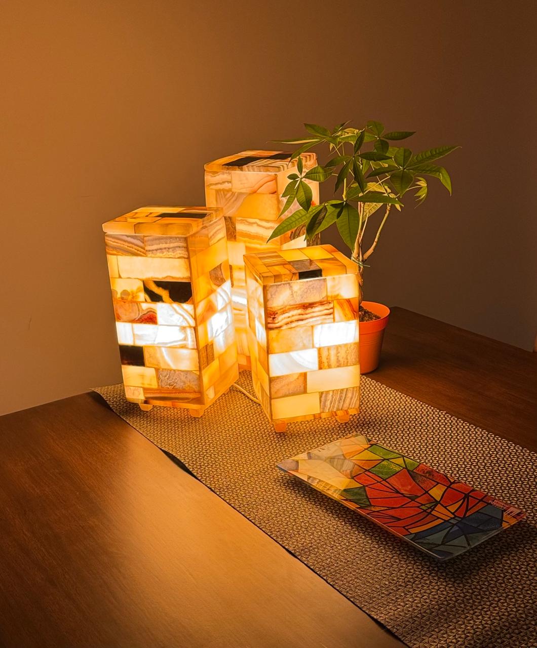 Three Egyptian alabaster mosaic lamps glowing on a dining table