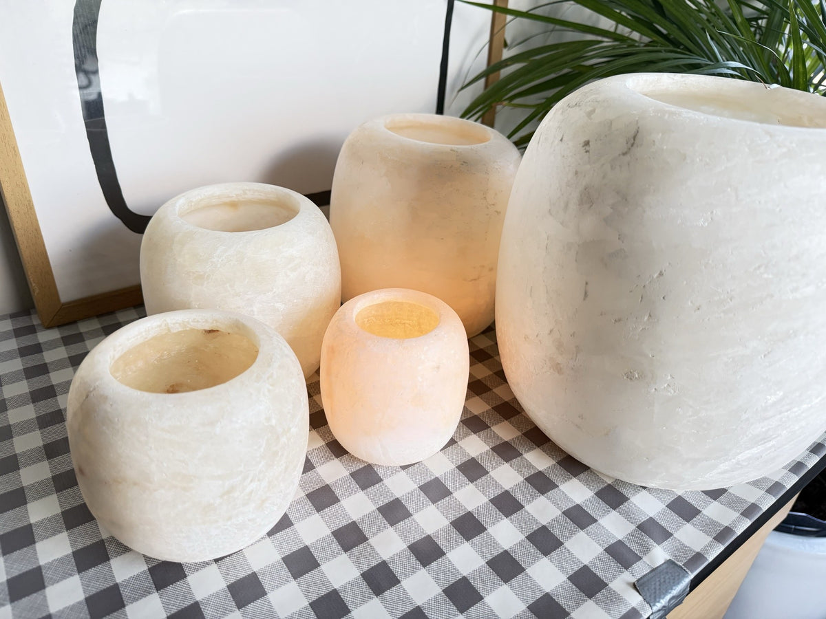The Pot, the five frosted pots from a closer angle, open rims and clouded matte stone, two of them lit and glowing orange inside
