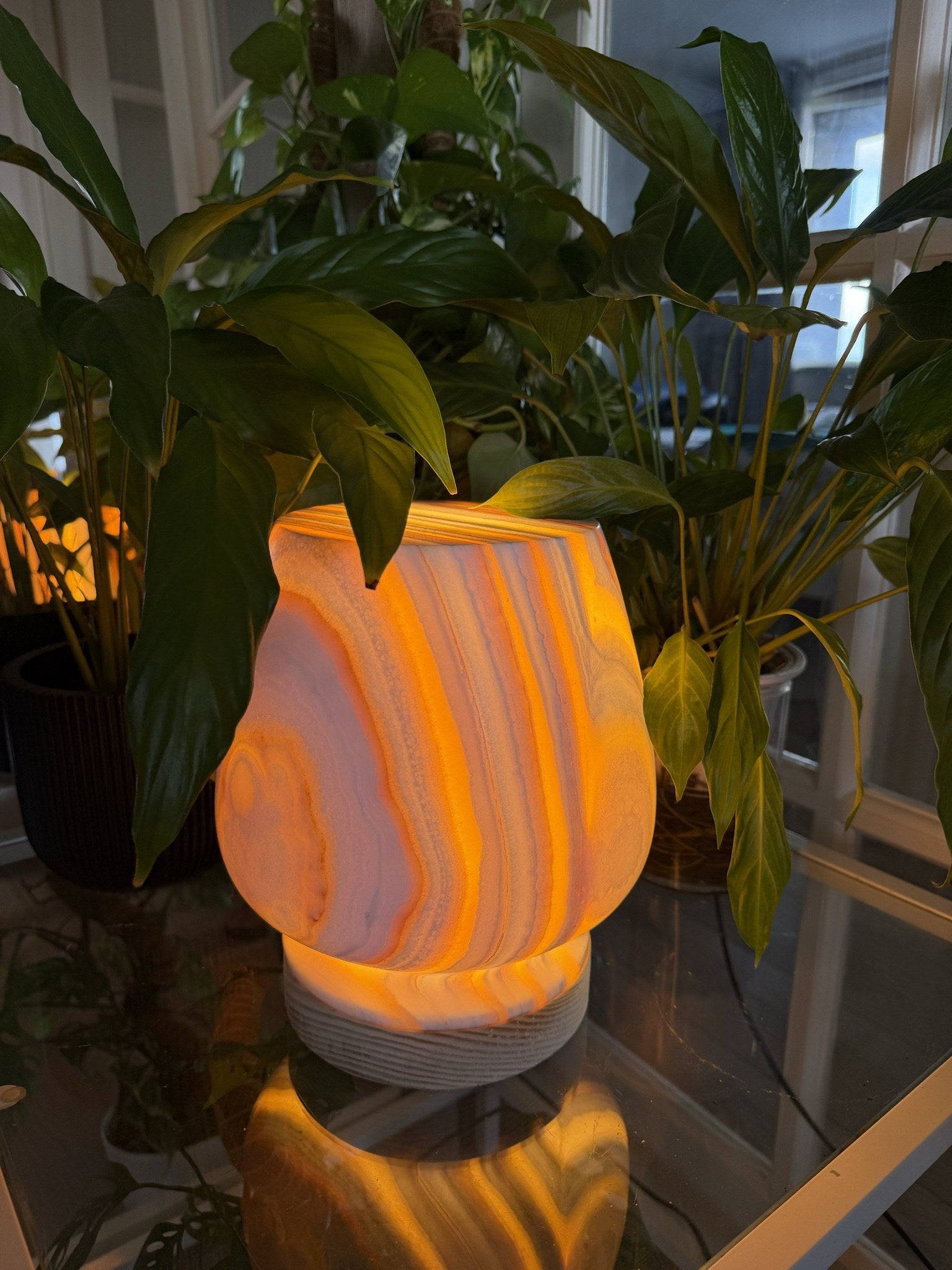 Close view of The Boulder lit, concentric amber and grey rings glowing through polished alabaster below a flat-cut top