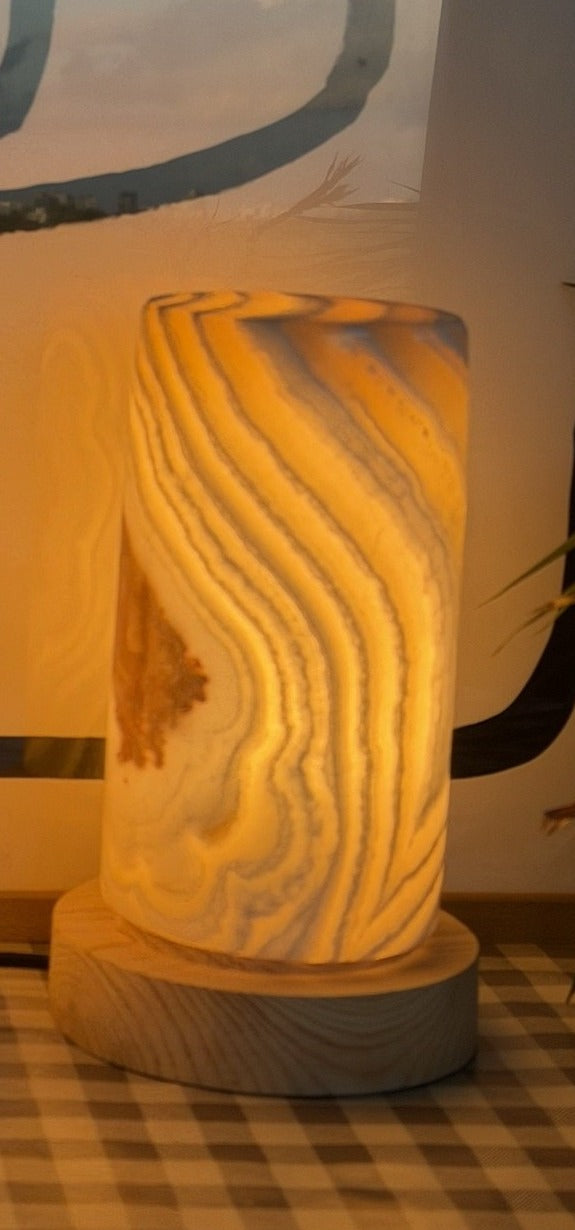 The Pillar L lit on its own, a tall alabaster column with sweeping wavy banding and a rust inclusion patch on one face