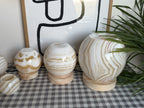The Sphere unlit from a closer angle, the three largest balls on pine bases showing cream and tan banding, a small orb at lower left