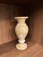Decorative vase with marble-like pattern on a wooden shelf in natural light