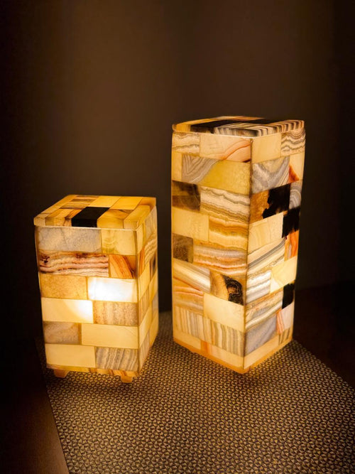 Mosaic Cube Pair lit, close view of the medium and large rectangular tile lamps, banded and dark tiles glowing, on a woven mat