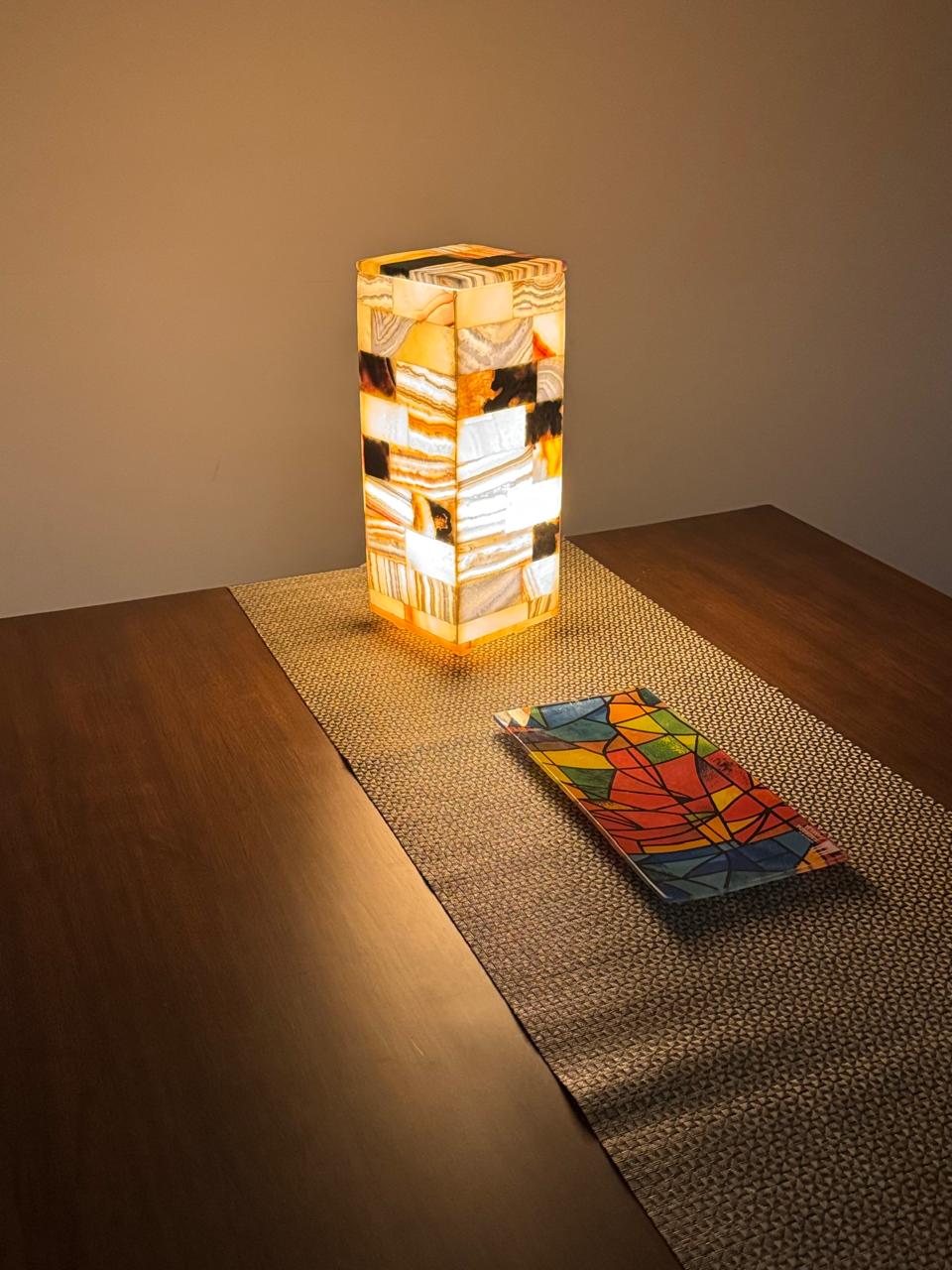 Decorative alabaster lamp on a wooden table with a colorful glass plate